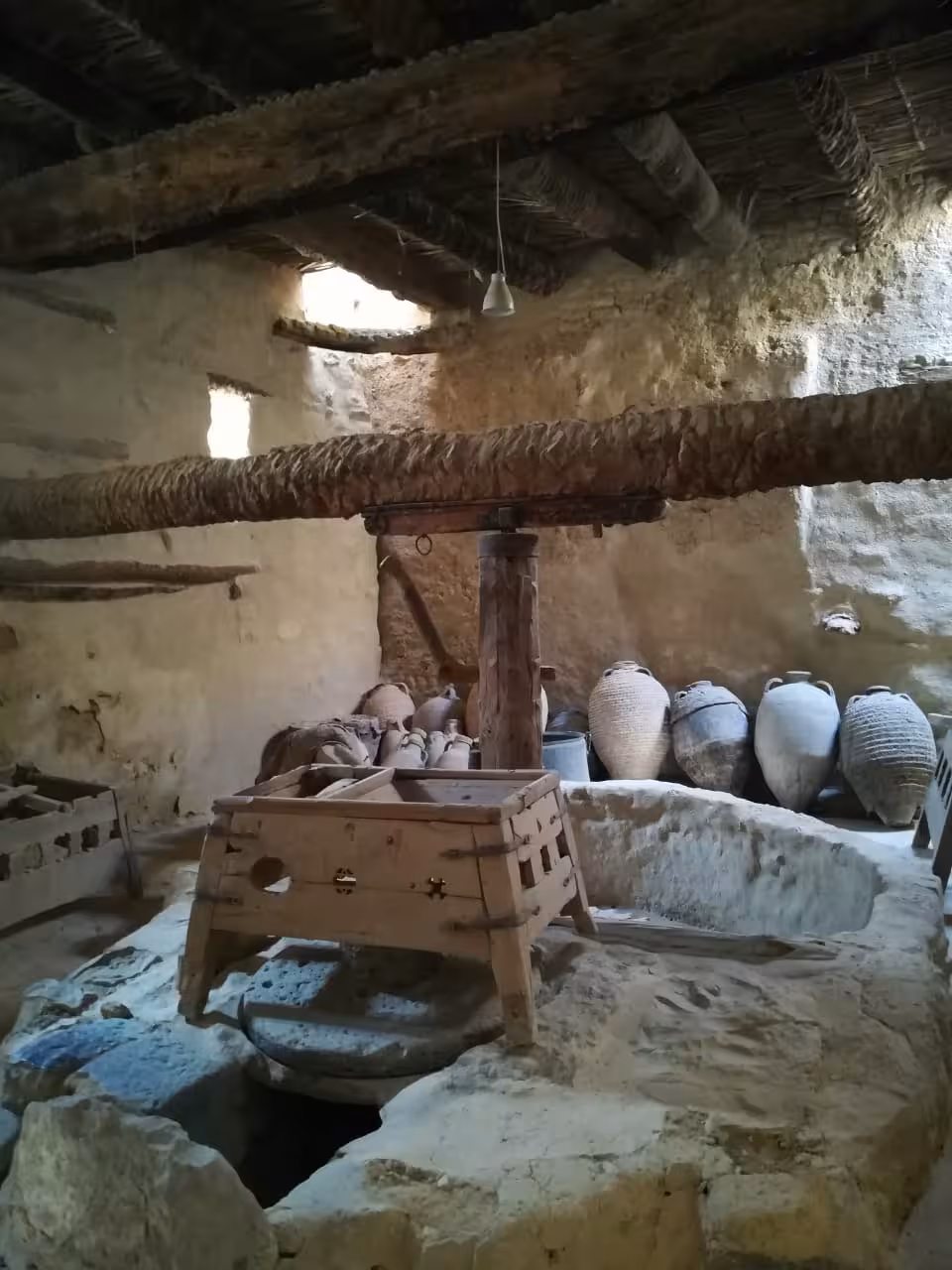 Ancient stone room with clay amphorae and wooden press inside a Red Sea monastery, Egypt