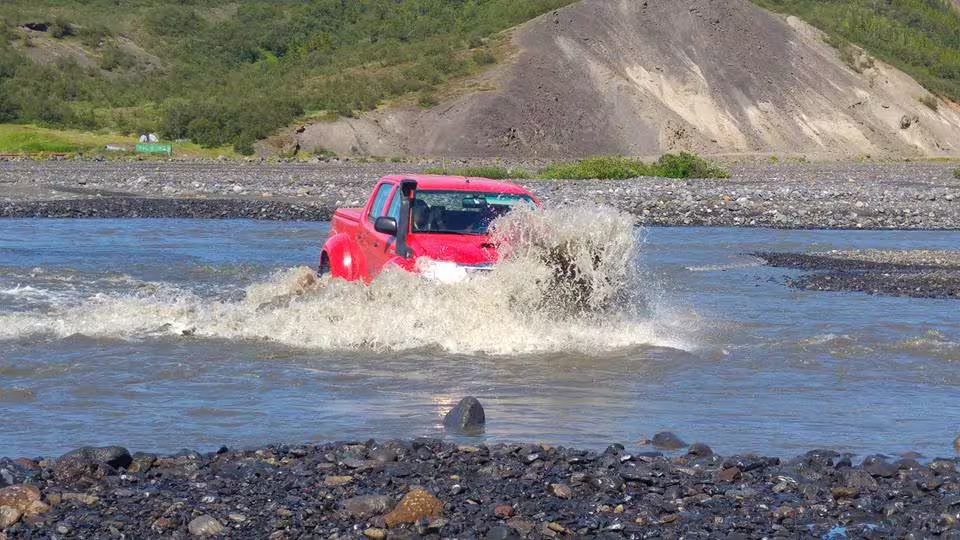 Red super jeep crossing a glacial river in Iceland's volcanic highlands near Thorsmork