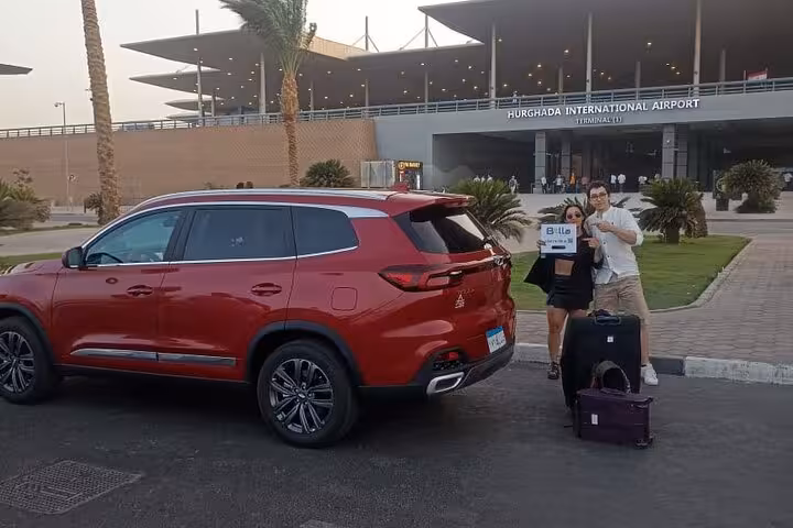 Red AC SUV pickup at Hurghada International Airport with meet and greet sign for private hotel transfer