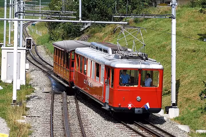 Red Swiss train traveling through scenic countryside on a historic railway route, ideal for customizable tours.