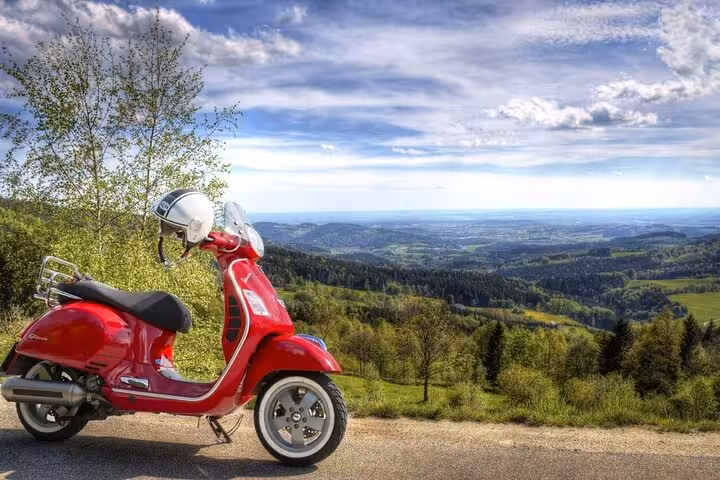 Red Vespa parked with scenic Tuscan hills in the background, ideal for Chianti small group Vespa adventures.