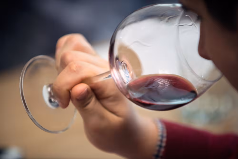 Close-up of a person savoring red wine aroma during a small-group blending experience, highlighting sensory exploration.