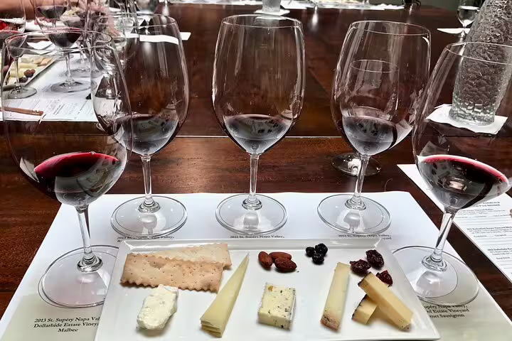 Wine tasting flight with four red wine glasses and cheese charcuterie board on white platter