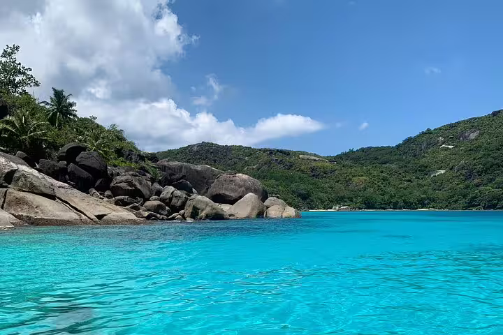 Scenic view of rocky coastline and lush greenery under a clear sky on a Reef Safari snorkeling day trip.