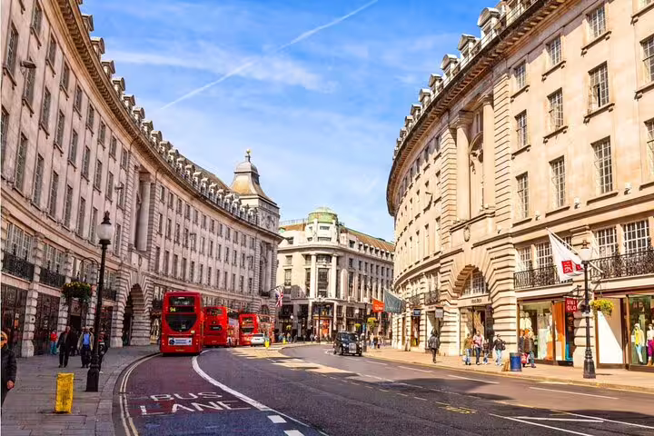 Red double-decker buses on Regent Street London with curved Georgian architecture and shops
