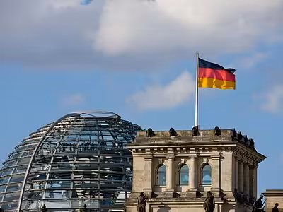 German flag flying atop the Reichstag building with its iconic glass dome in Berlin