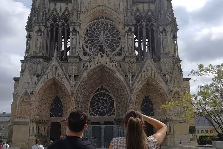 Couple admiring the Gothic façade of Reims Cathedral with rose window and sculpted portals