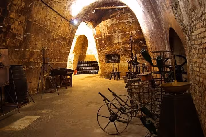 Ancient stone vaulted cellar in Reims with vintage winemaking equipment and champagne bottles