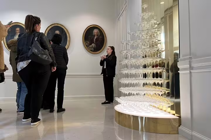 Guided Champagne house tour in Reims with visitors beside a wall of flutes on Paris day trip