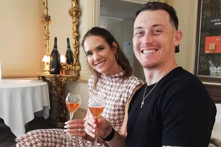 Couple smiling and toasting with champagne glasses during a guided tasting in Reims, France
