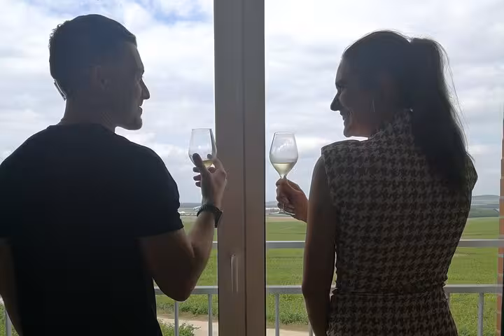 Couple toasting with white wine glasses overlooking green vineyards during Reims champagne tasting tour