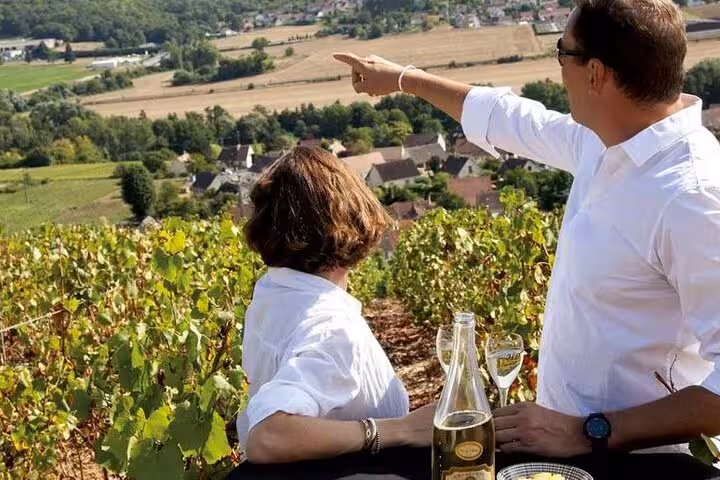 Couple enjoying champagne tasting overlooking Reims vineyards and village on a sunny day