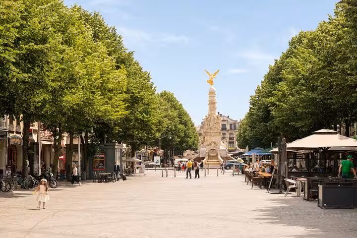 Sunny pedestrian boulevard in Reims with golden angel monument and tree-lined promenade