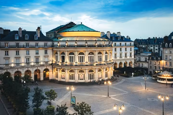Rennes Opera House illuminated at dusk with grand neoclassical facade and copper dome overlooking a stone plaza