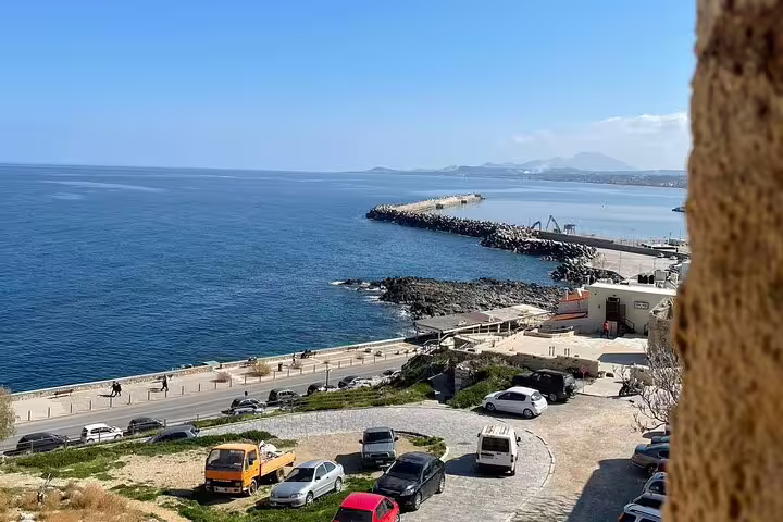 Scenic coastal view of Rethymno harbor with clear blue sea and distant landscapes, perfect for a private tour.
