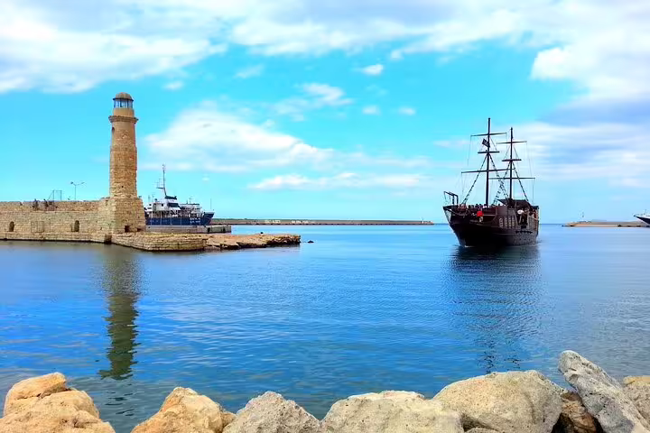 Scenic view of Rethymno harbor with historic lighthouse and pirate ship, perfect for exploring Chania and Kournas Lake on a private tour.