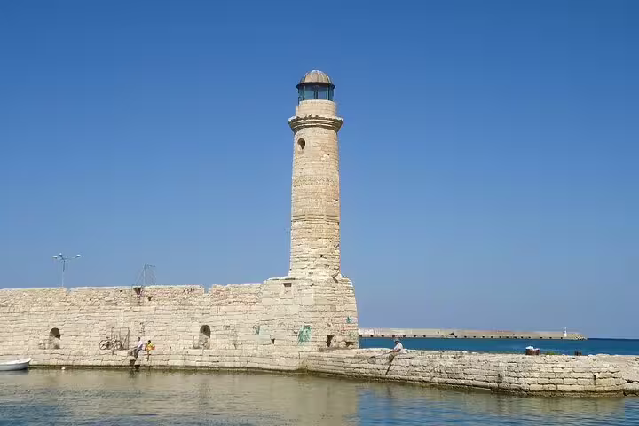 Historic lighthouse on the Rethymno harbor, set against a clear blue sky, symbolizing Crete's maritime heritage.
