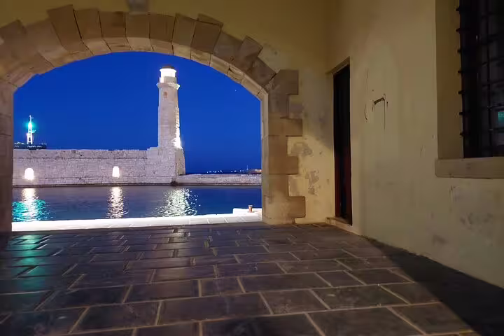 Historic stone lighthouse viewed through an archway in Rethymno at night, a highlight of the private Chania tour.