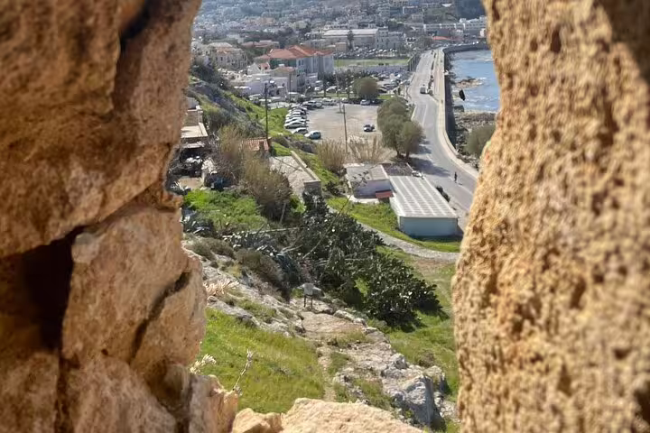 View of Rethymno Town through ancient stone walls on a private tour from Chania, showcasing scenic coastal roads and architecture.