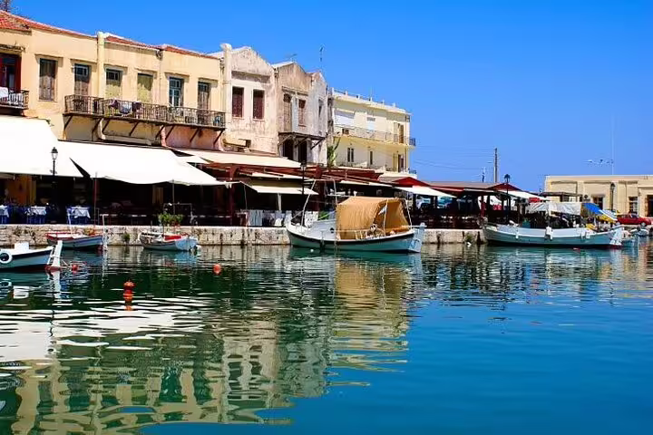 Scenic view of Rethymno's charming Venetian harbor with colorful boats and waterfront cafes on a sunny day in Crete.