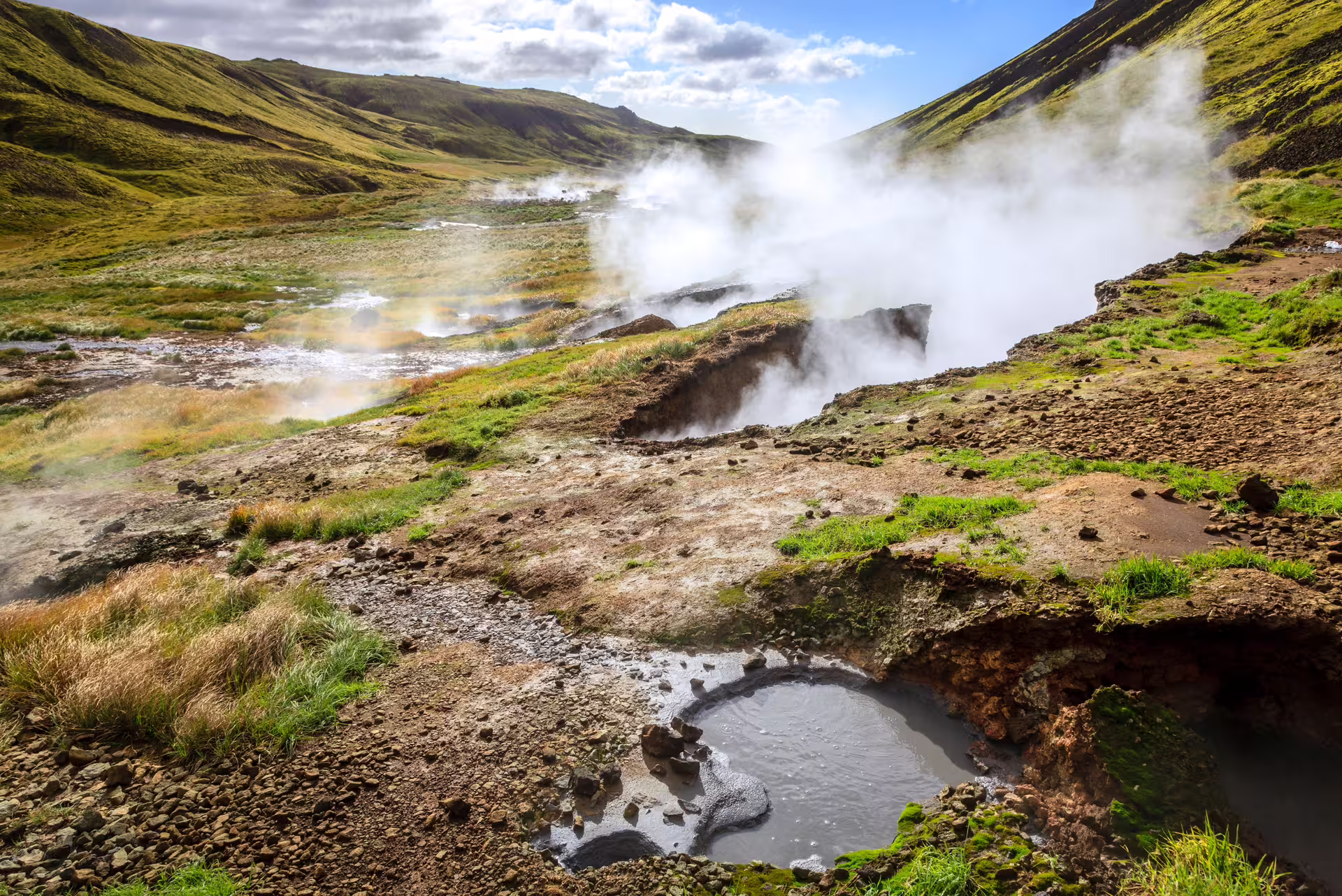 Steaming geothermal vents and bubbling mud pools in Reykjadalur Valley on a private hot river hike in Iceland