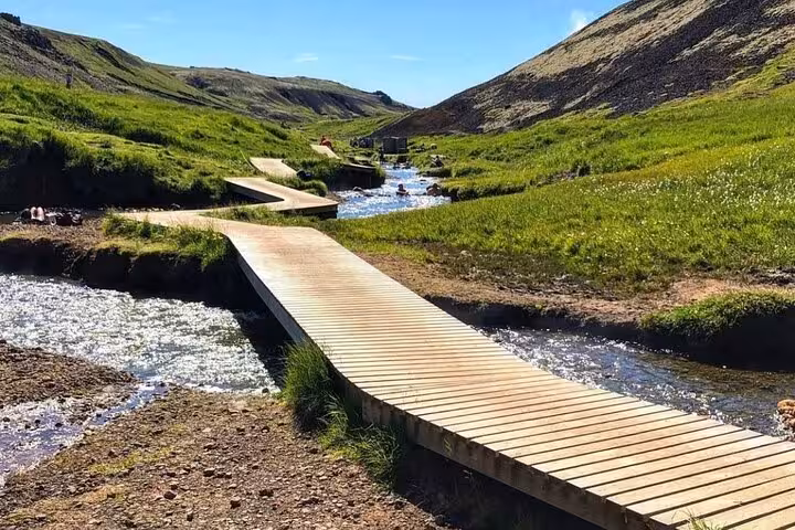 Wooden boardwalk crossing a geothermal hot spring stream in Reykjadalur valley, Iceland