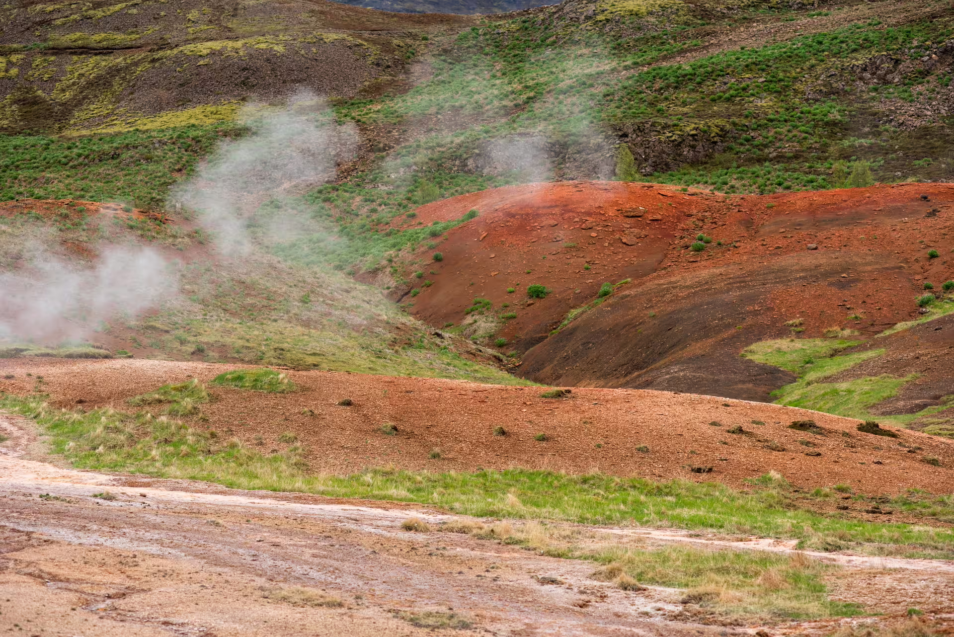 Colorful rhyolite hills with rising steam on the private Reykjadalur Hot River Hike near Hveragerdi, Iceland