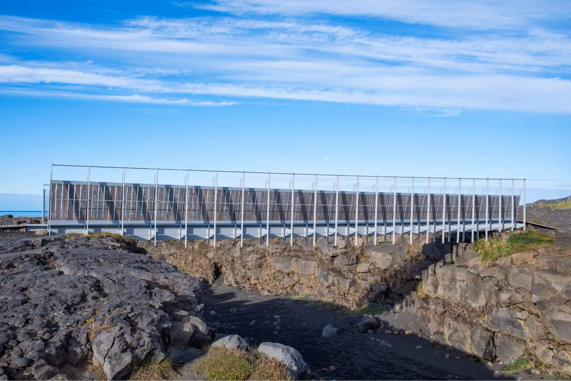 Modern bridge structure over volcanic lava rock formations at Reykjanes Geopark, Iceland