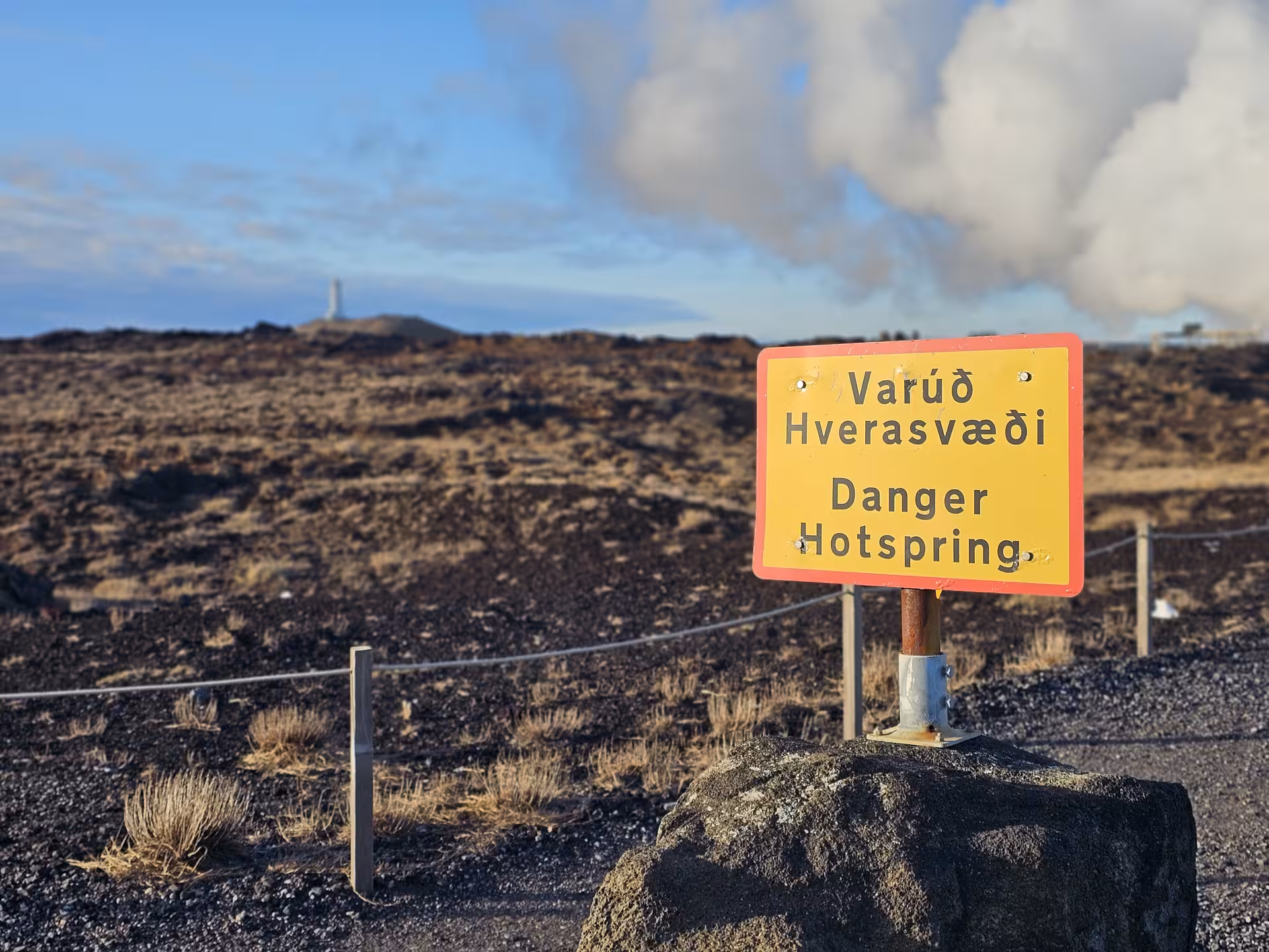 Yellow danger hotspring warning sign in Icelandic and English at Reykjanes Geopark lava field