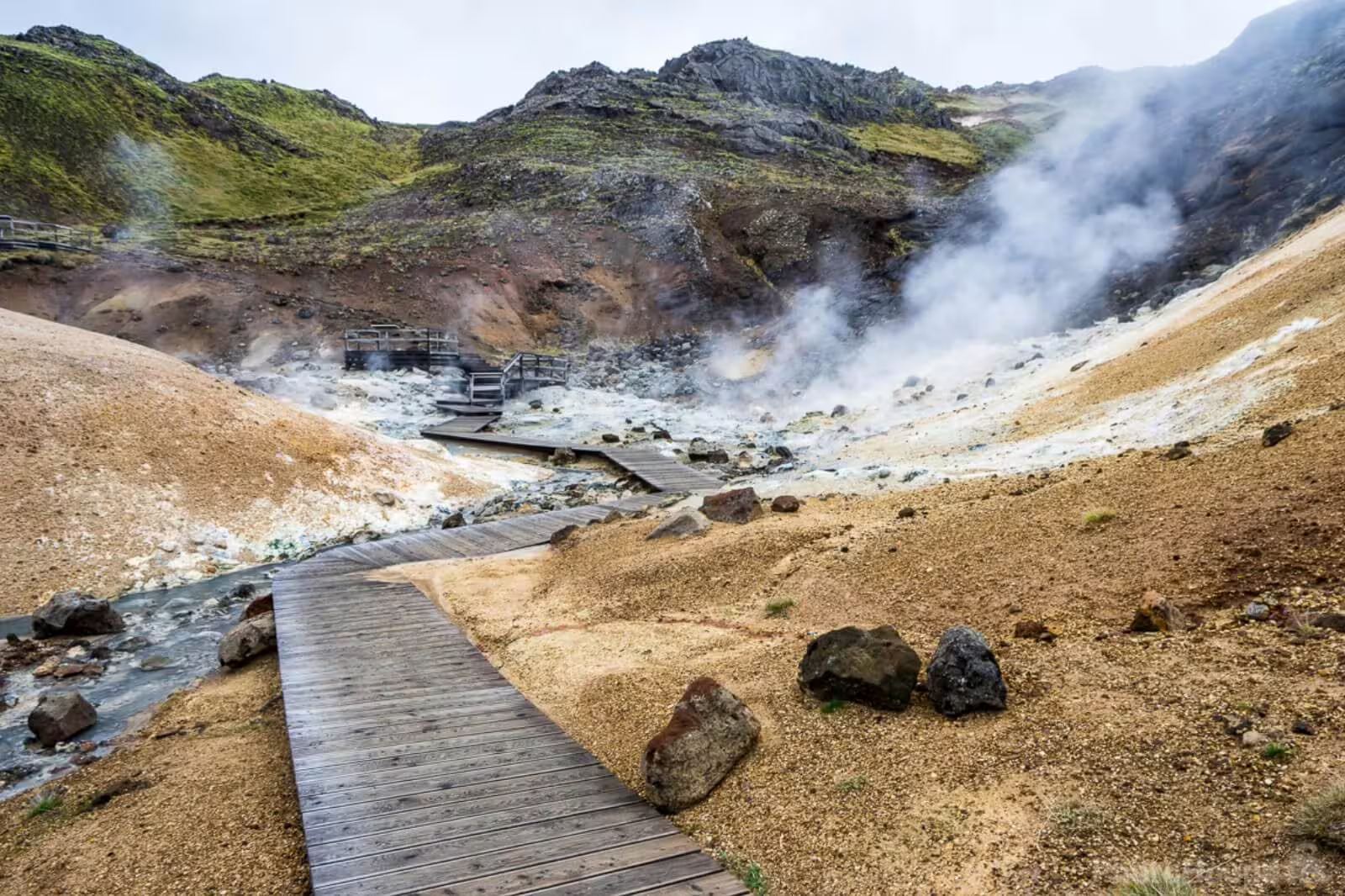Wooden boardwalk leading through steaming geothermal vents at Reykjanes Geopark Iceland