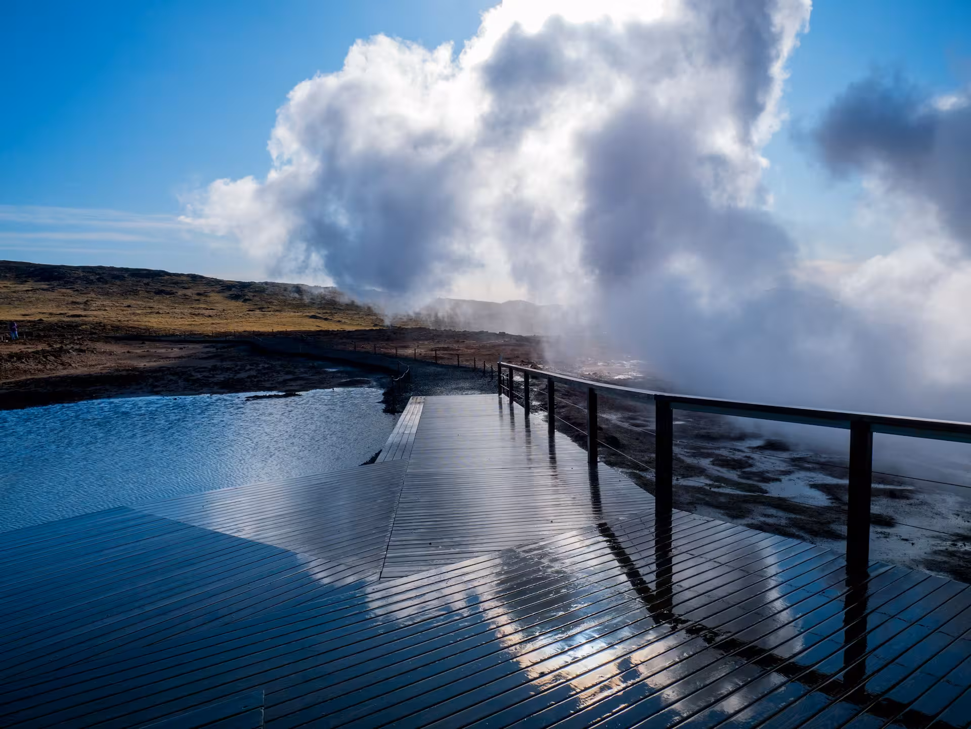 Wooden boardwalk over geothermal hot springs with rising steam at Reykjanes Geopark, Iceland