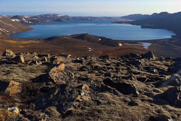 Rocky volcanic landscape overlooking a blue lagoon lake in Reykjanes Iceland with mountains in background