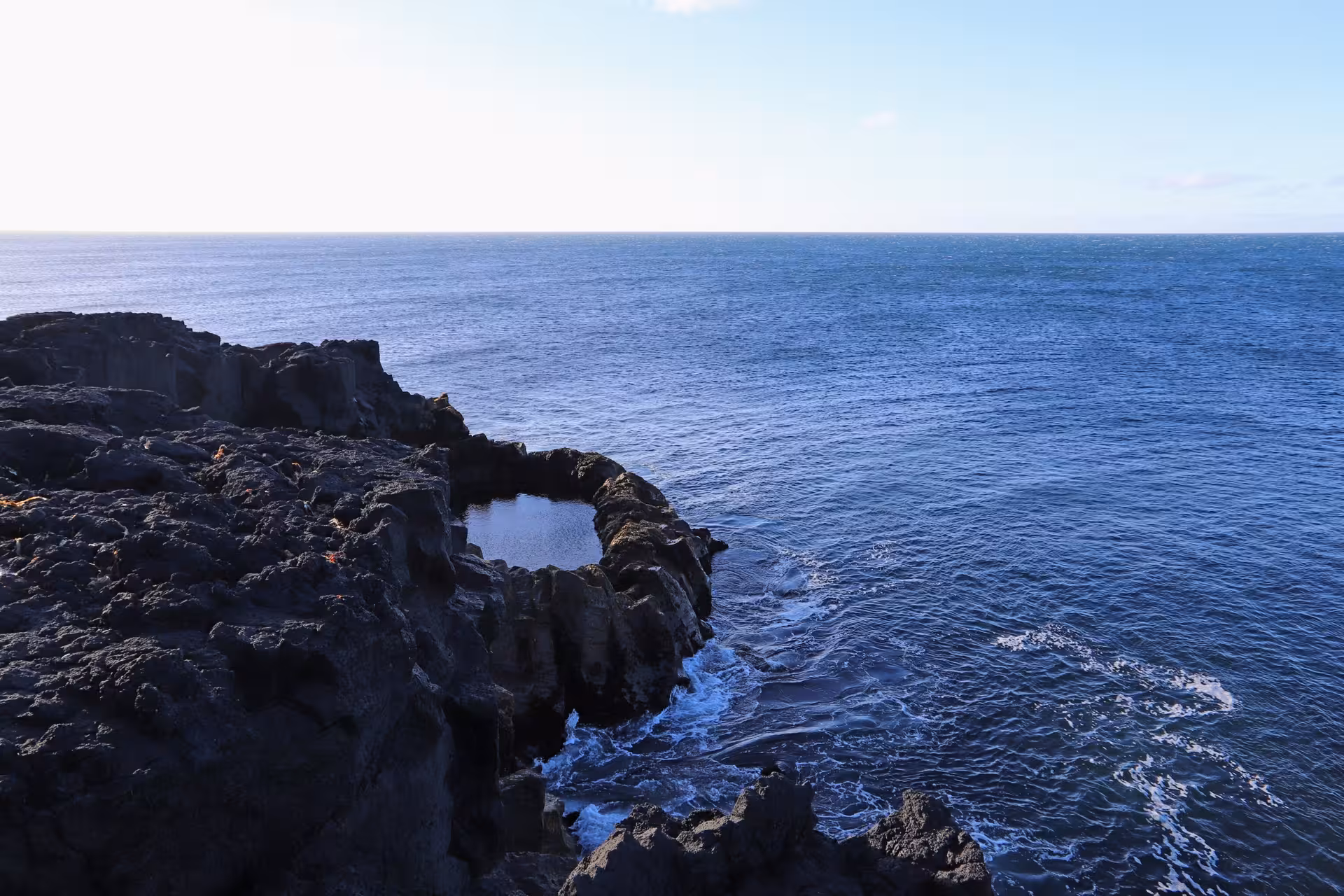 Black volcanic lava rock coastline with natural tidal pool along Reykjanes Peninsula, Iceland