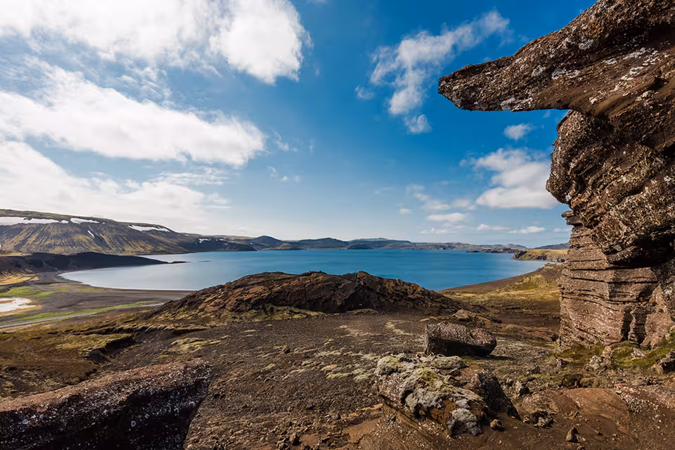 Volcanic lava field landscape with blue lake and snow-capped mountains in Reykjanes Peninsula, Iceland