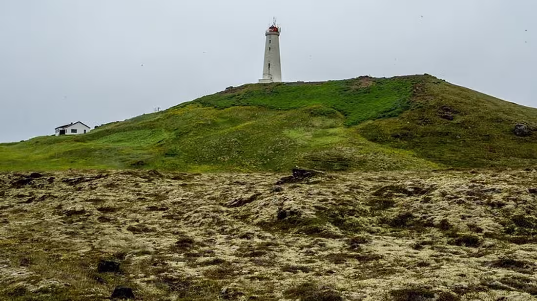 A tall lighthouse on a grassy hill