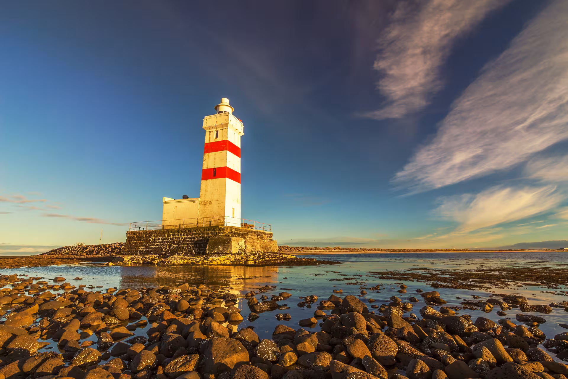 Iconic Reykjanes lighthouse at sunset with rocky coastline, perfect for a scenic private tour in Iceland.
