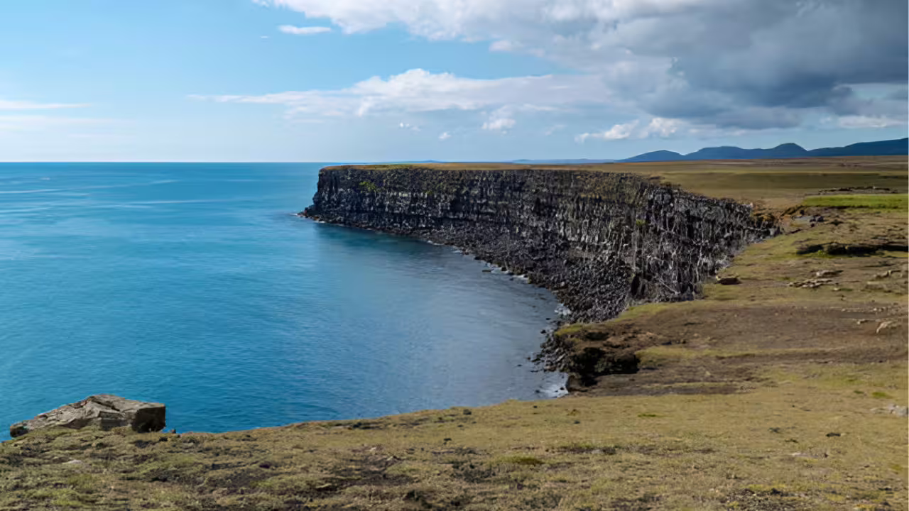 Dramatic basalt sea cliffs along the Reykjanes Peninsula coastline with calm blue Atlantic waters