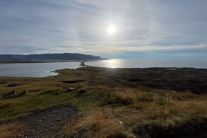 Panoramic coastal view of Reykjanes Peninsula with sunlit fjord, green hillside, and distant cliffs in Iceland