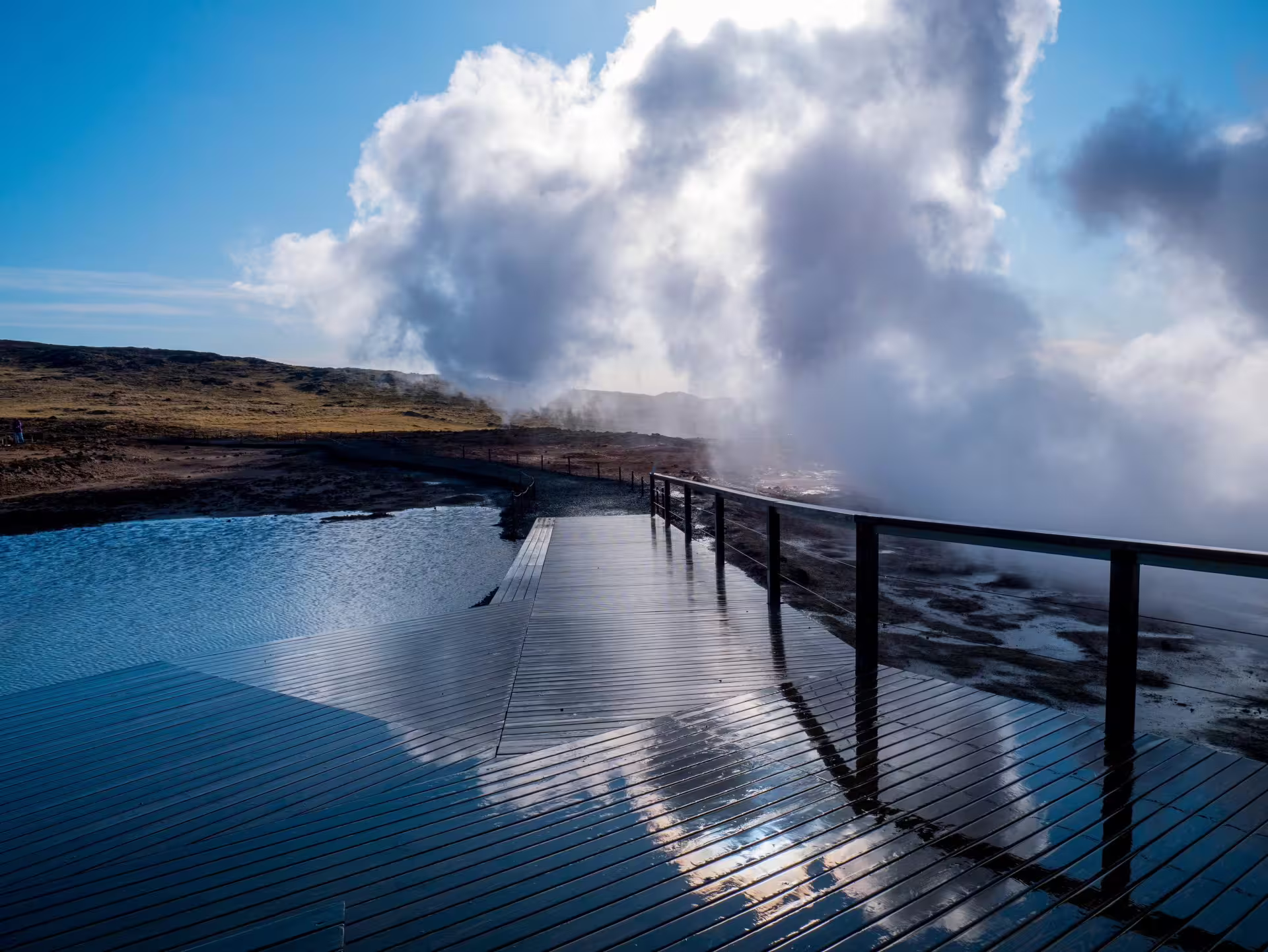 Wooden boardwalk over geothermal hot springs with rising steam on Reykjanes Peninsula, Iceland