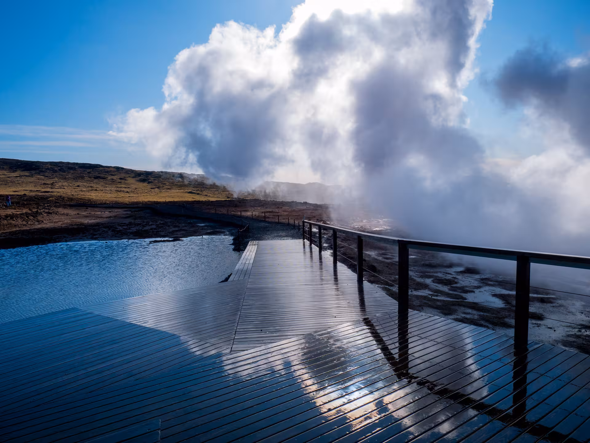 Wooden boardwalk over geothermal hot spring with rising steam on Reykjanes Peninsula, Iceland