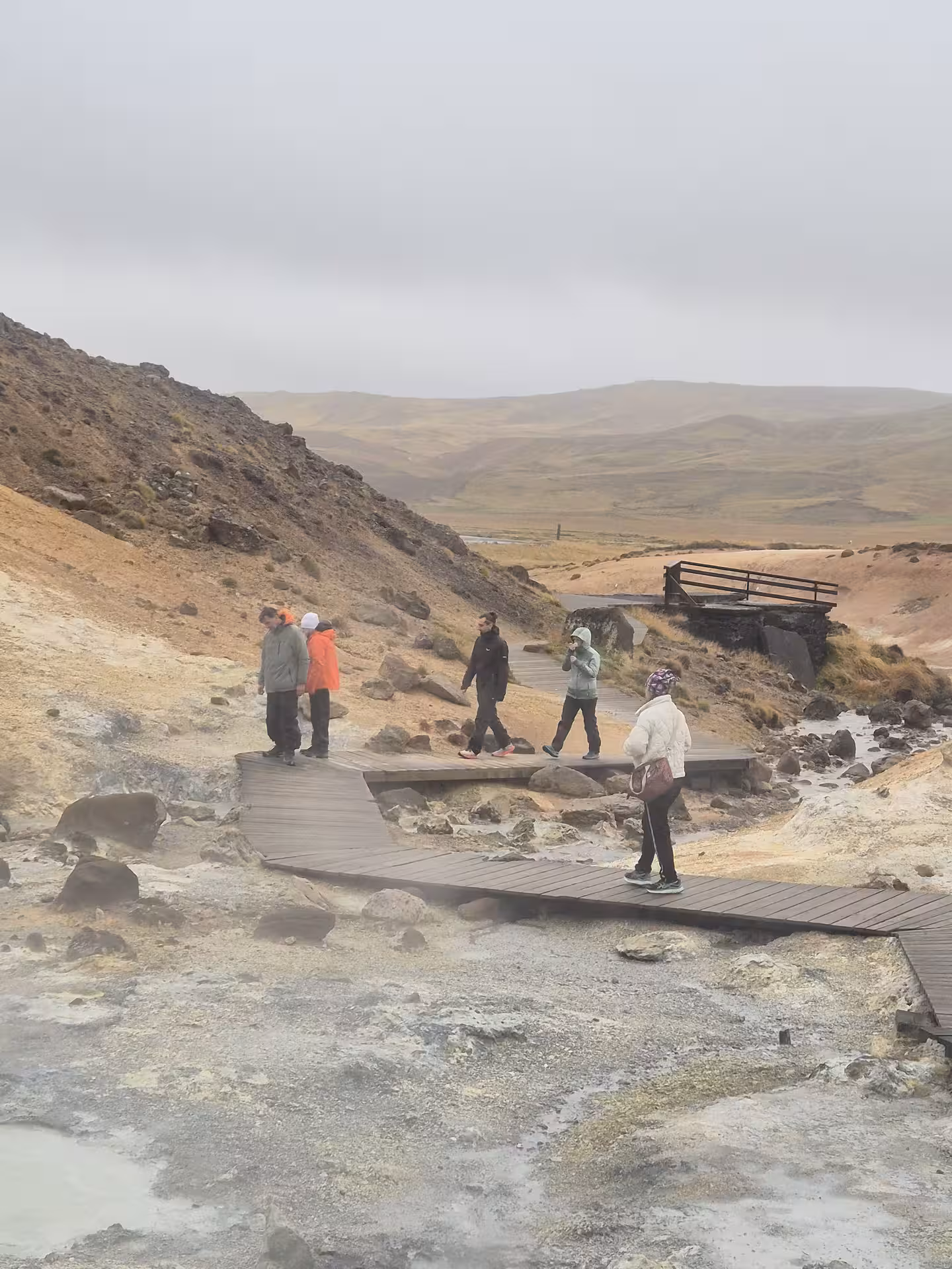 Tourists walking on wooden boardwalk through geothermal area on Reykjanes Peninsula, Iceland