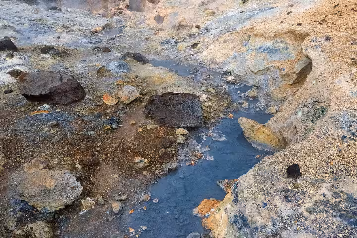 Steaming geothermal hot springs with colorful mineral deposits and volcanic rocks on Reykjanes Peninsula