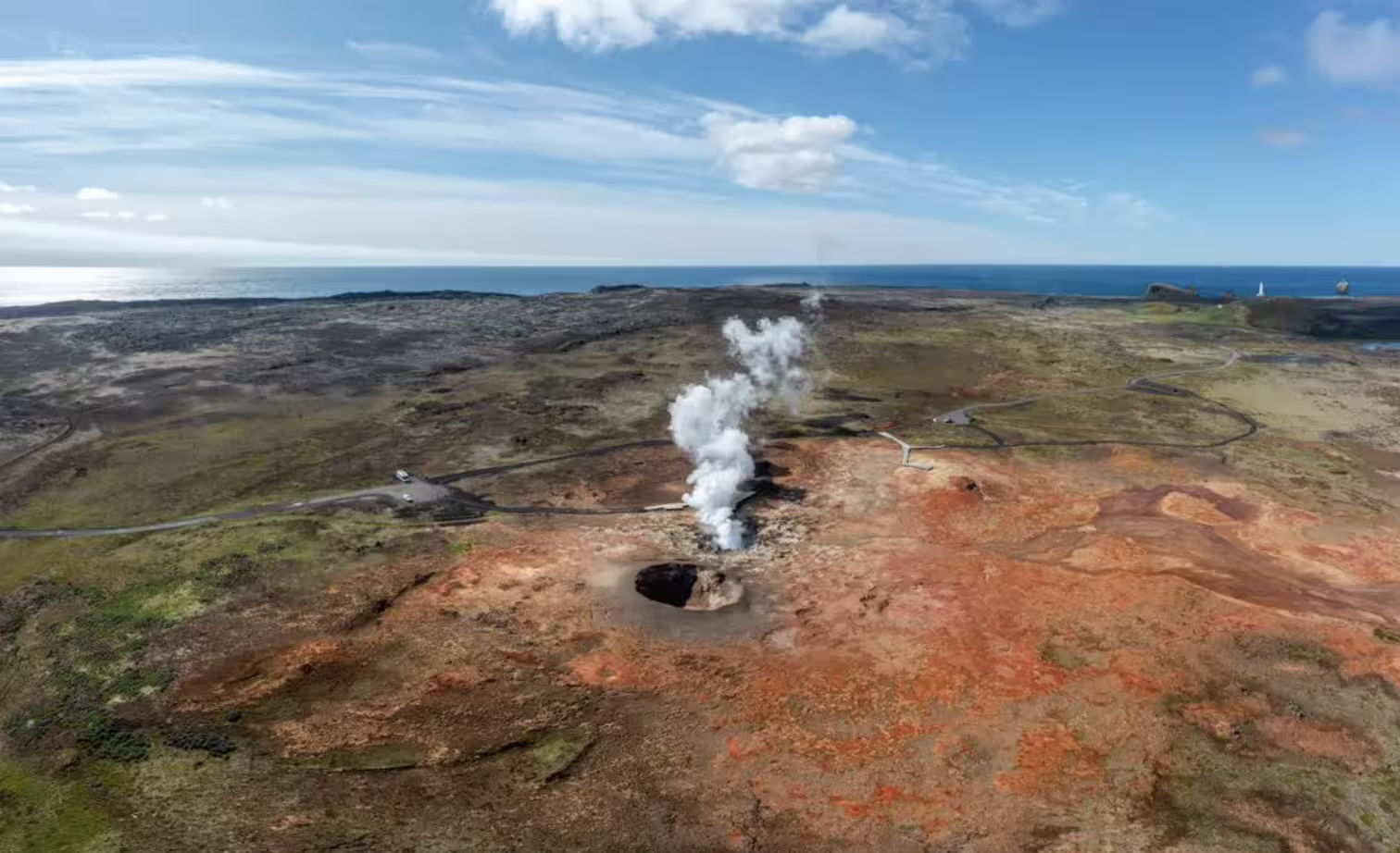 Aerial view of steaming geothermal vent on Reykjanes Peninsula with ocean horizon, Iceland