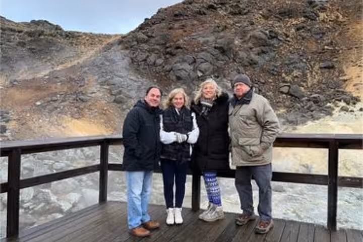Four tourists posing on a wooden viewing platform at a volcanic geothermal area on the Reykjanes Peninsula