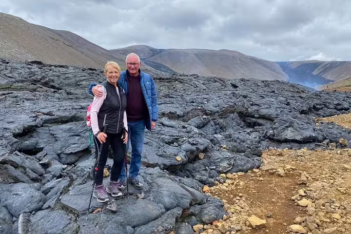 Couple posing on black lava fields with volcanic mountains in background on Reykjanes Peninsula