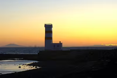 Lighthouse silhouette at golden sunset on Reykjanes Peninsula coastline, Iceland