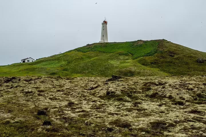 White lighthouse atop a green volcanic hill on the Reykjanes Peninsula, Iceland