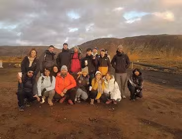 Group of tourists posing together on Reykjanes Peninsula volcanic landscape with hills in background