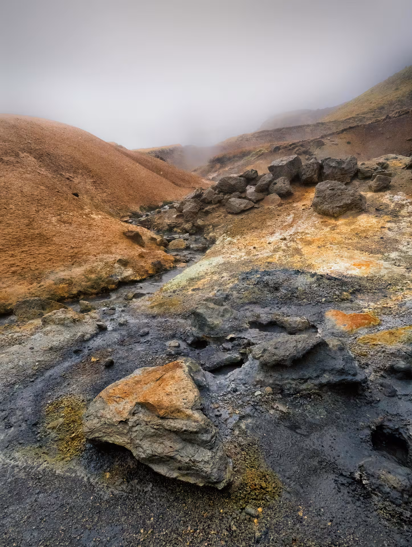 Colorful geothermal volcanic rocks and sulfur deposits on Reykjanes Peninsula, Iceland, with misty hills