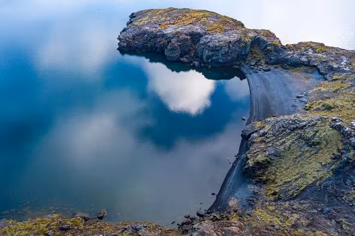 Volcanic black sand beach and turquoise lagoon with cloud reflections on Reykjanes Peninsula, Iceland